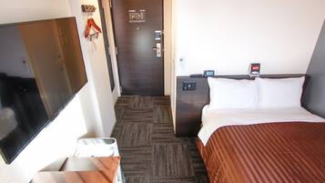 Habitación de hotel con cama, televisión, escritorio con silla, puerta y teléfono en la pared.