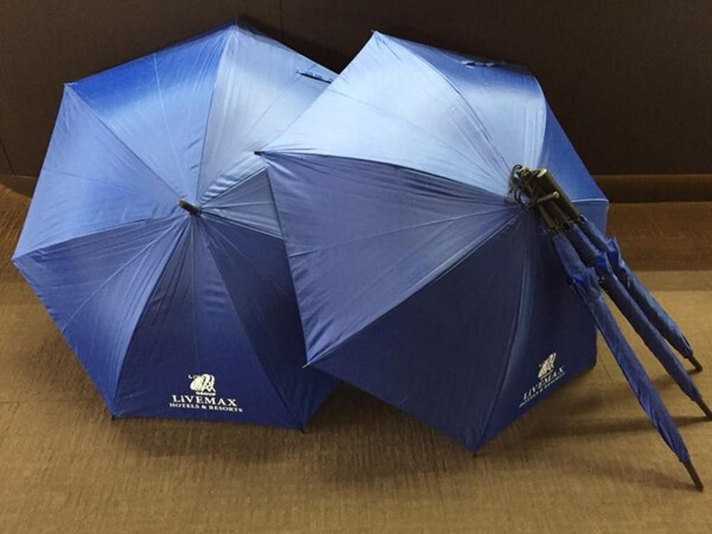 Two blue umbrellas with the LIVEMAX logo, placed on a wooden surface.