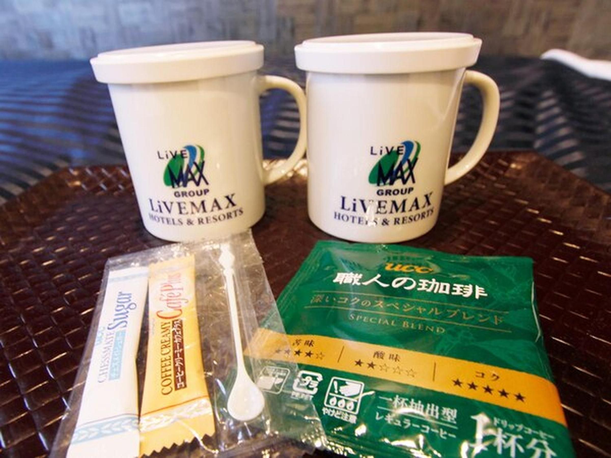 Two white mugs with the Livemax Group logo, a packet of coffee cream, and a packet of a special blend coffee.