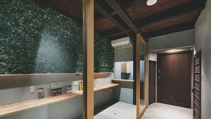 A modern bathroom with a green wall, wooden shelves, and a dark wooden door. - Seven Stay Ouchi (Kyoto)