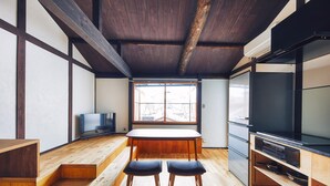 A modern kitchen with a wooden table, two stools, a TV, and a built-in oven. - Seven Stay Ouchi (Kyoto)