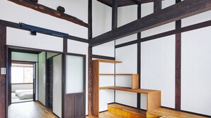 A traditional Japanese-style room with tatami flooring, a sliding door, and built-in wooden shelves. - Seven Stay Ouchi (Kyoto)
