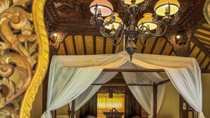 A four-poster canopy bed with ornate wooden headboard and footboard, a chandelier, and a decorative mirror above the bed. - Shanti Natural Panorama View Hotel (Sukasada)