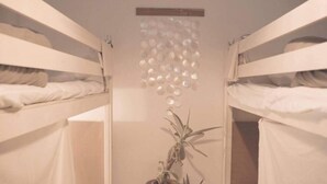 Habitación con literas, lámpara colgante y planta en maceta.
