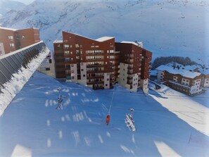 Ein Skigebiet mit einem modernen Gebäude, Skipfällen und verschneiten Pisten.