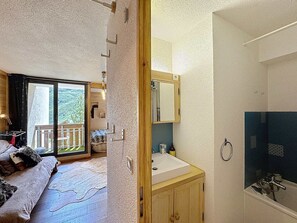 Ein Schlafzimmer mit großem Fenster, einem hölzernen Bett und Blick auf einen Balkon.