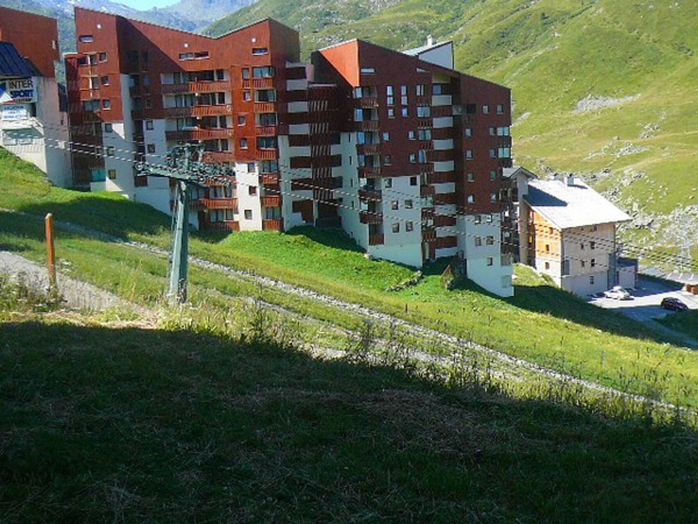 Un hôtel à plusieurs étages doté d’une architecture moderne, avec des balcons et une façade combinant des éléments en brique et des murs blancs.