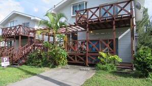 A two-story house with a wooden deck and a covered porch. - Holiday House Sumire (Onna)