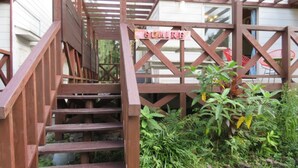 A wooden staircase leading to a covered area with a sign that reads "SUMIRF". - Holiday House Sumire (Onna)