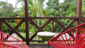 A wooden deck with two red chairs and a small round table. - Holiday House Sumire (Onna)