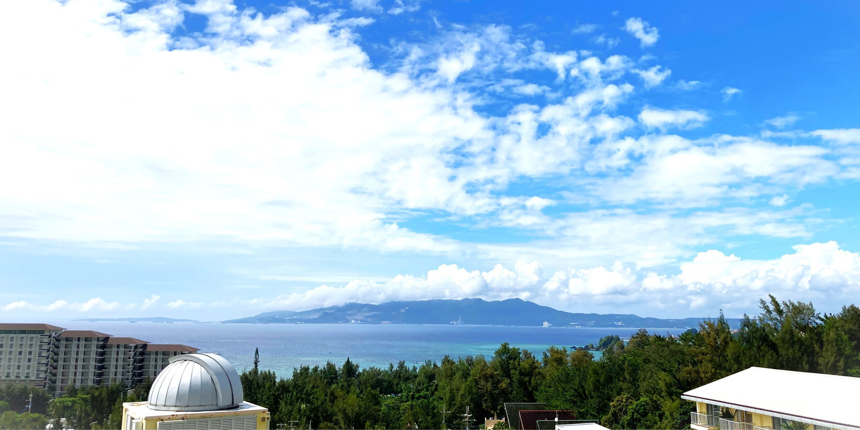 A coastal view with a clear sky, a large body of water, and distant mountains.