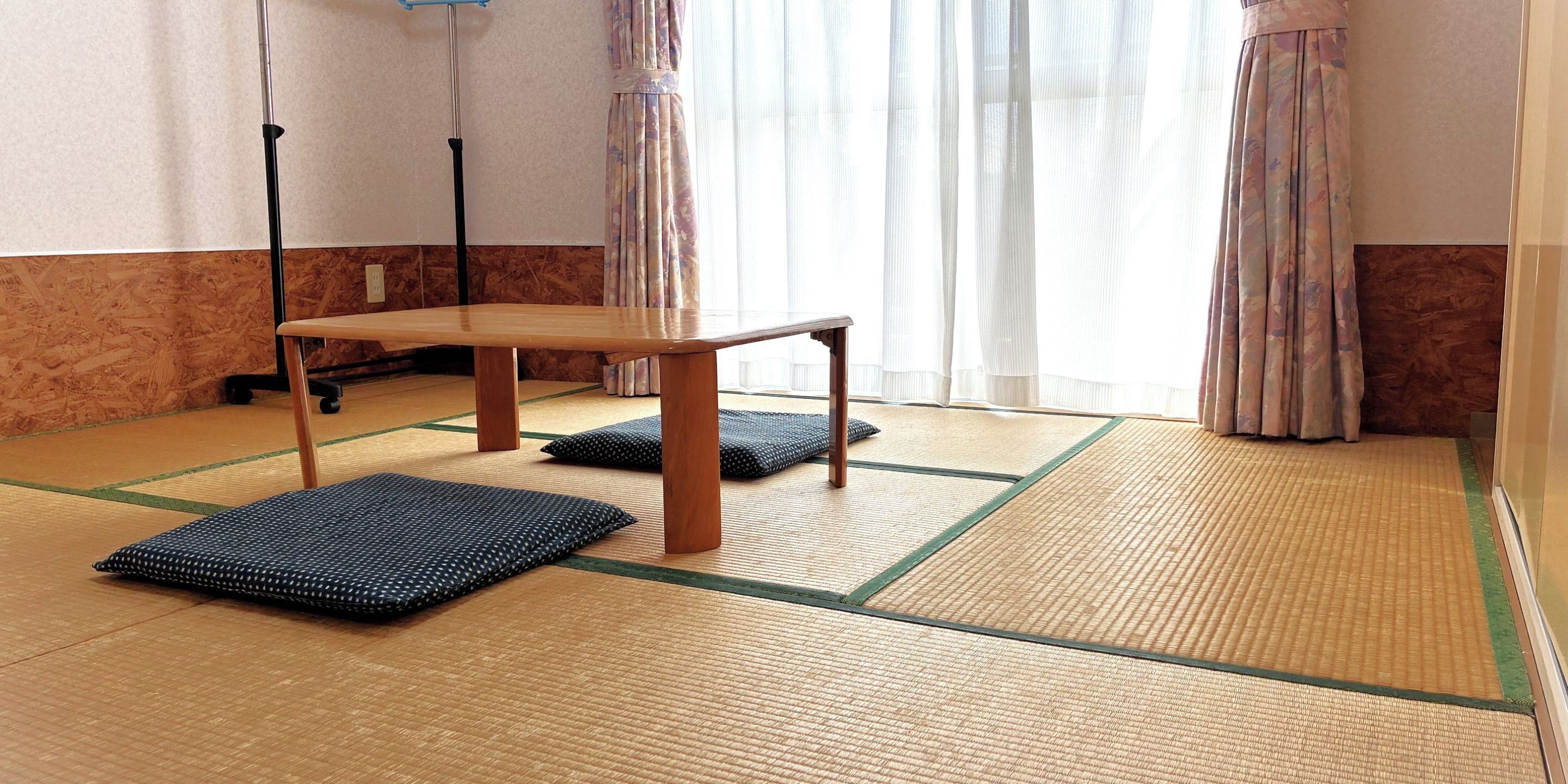 Una stanza con tatami, un tavolo di legno e cuscini.