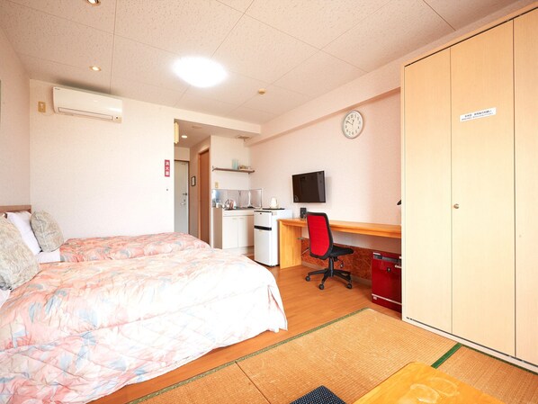 A hotel room with a bed, a desk with a chair, a television, a wardrobe, and a kitchenette. - Condo hotel Shimanchu Club (Onna)