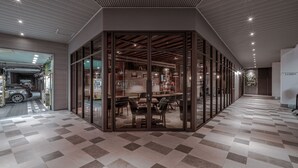 A modern interior with a checkered floor, a glass partitioned area with tables and chairs, and a ceiling with recessed lighting. - Somer Chew Hotel (Tainan)