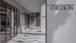 A check-in area with a tiled floor, glass doors, and a sign reading "CHECK IN". - Somer Chew Hotel (Tainan)