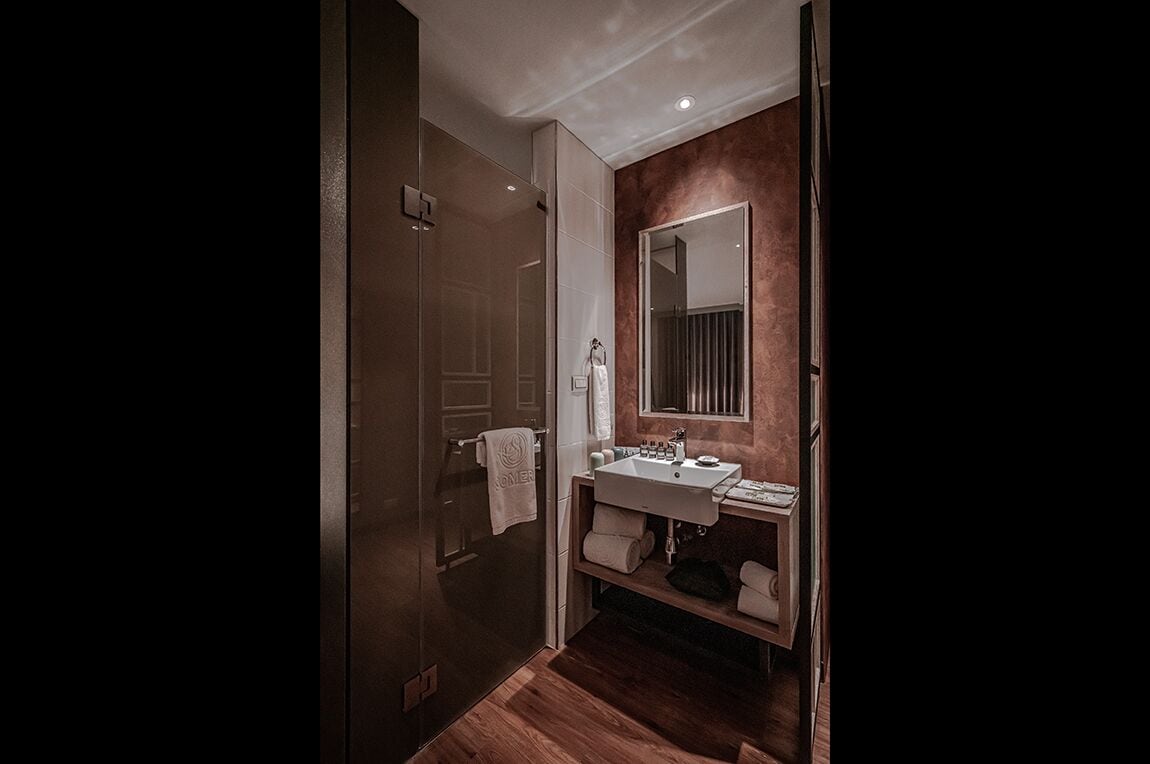 Une salle de bain moderne avec une douche à l’italienne en verre, un meuble-lavabo avec un miroir et un plancher en bois.
