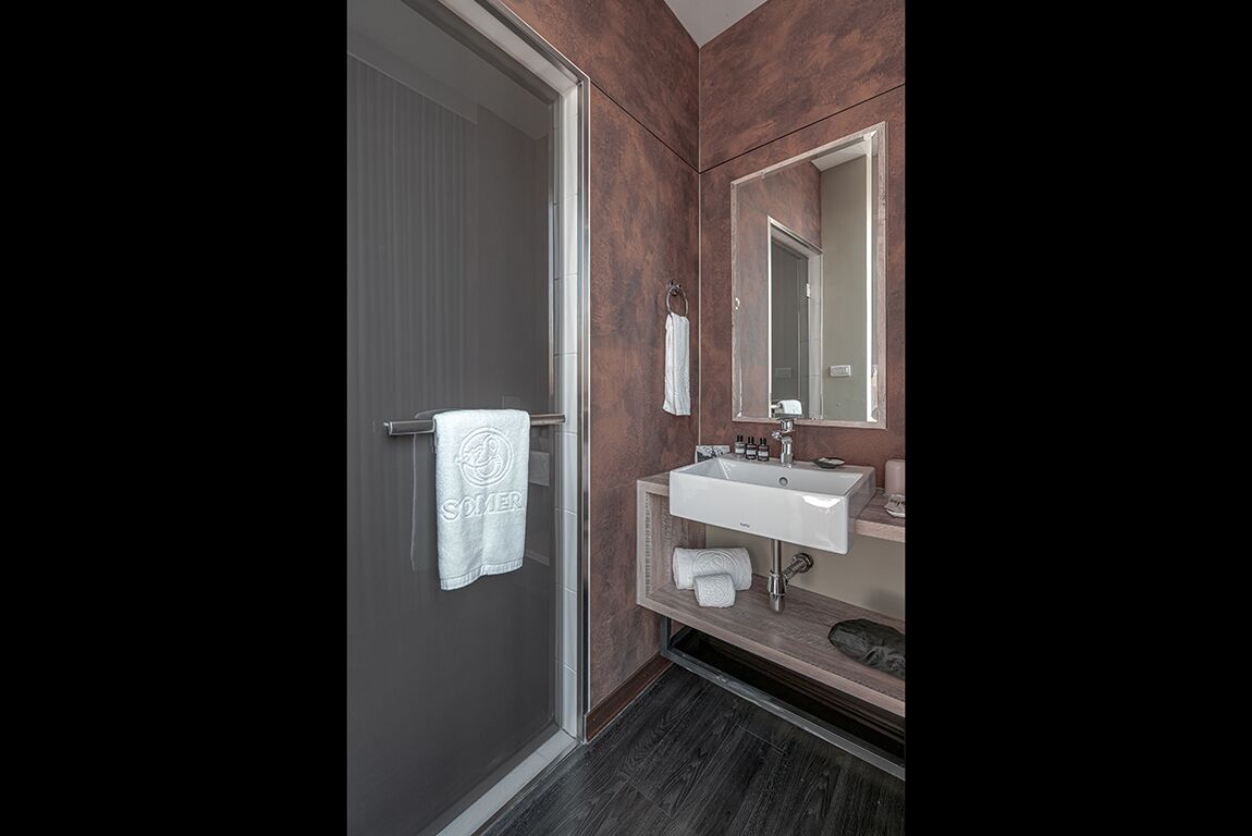 A modern bathroom with a glass shower door, a white sink, and a large mirror.