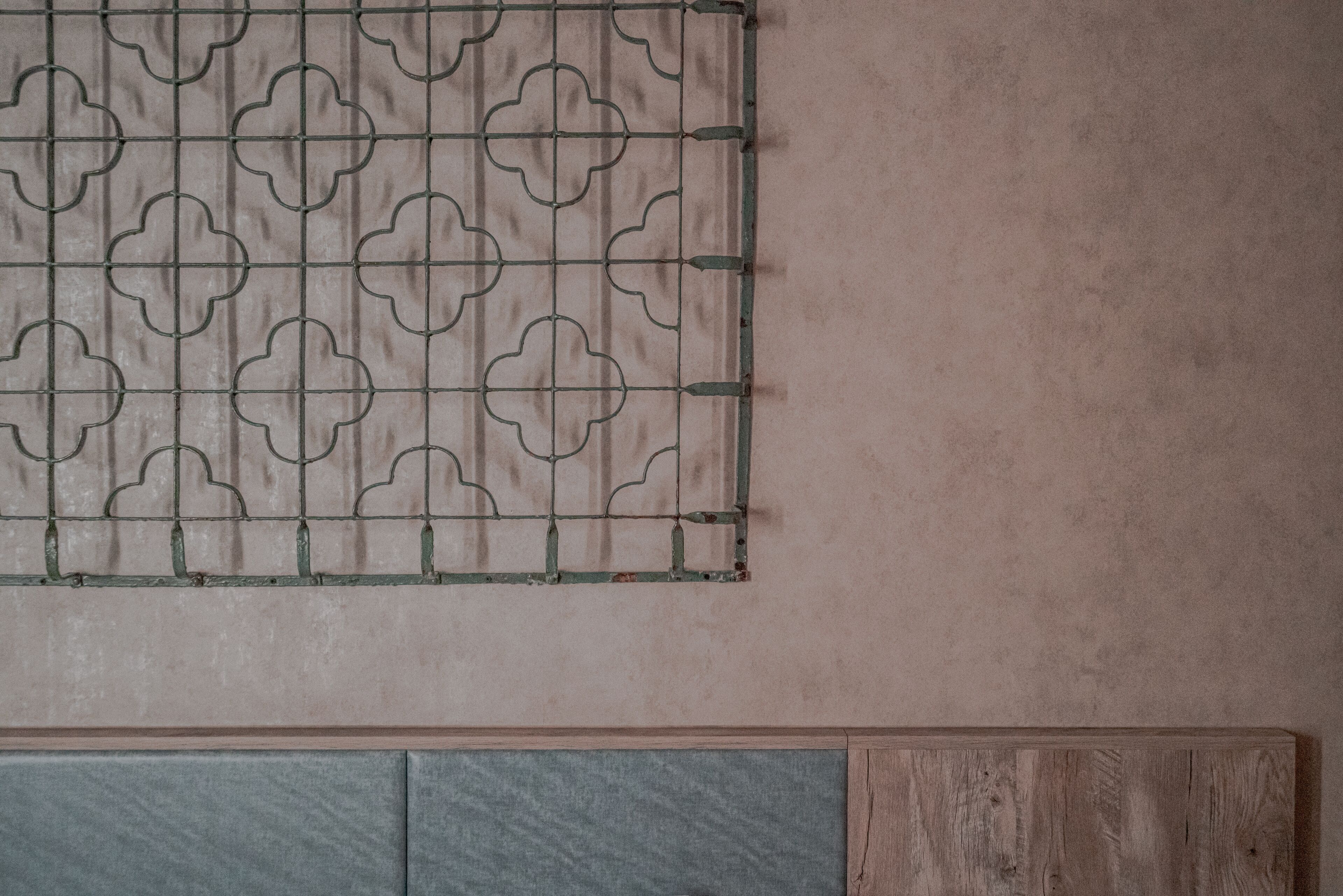 A wall with a metal grid pattern and a wooden panel below.