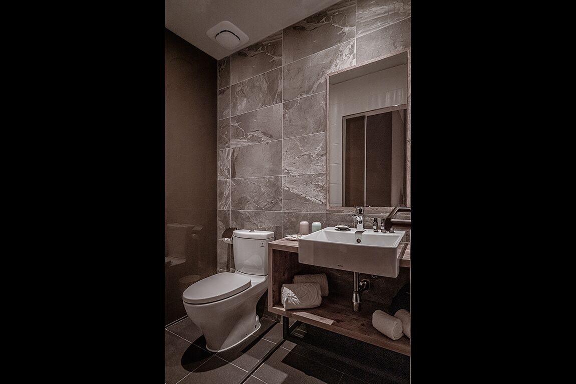 A modern bathroom with a toilet, sink, and mirror.