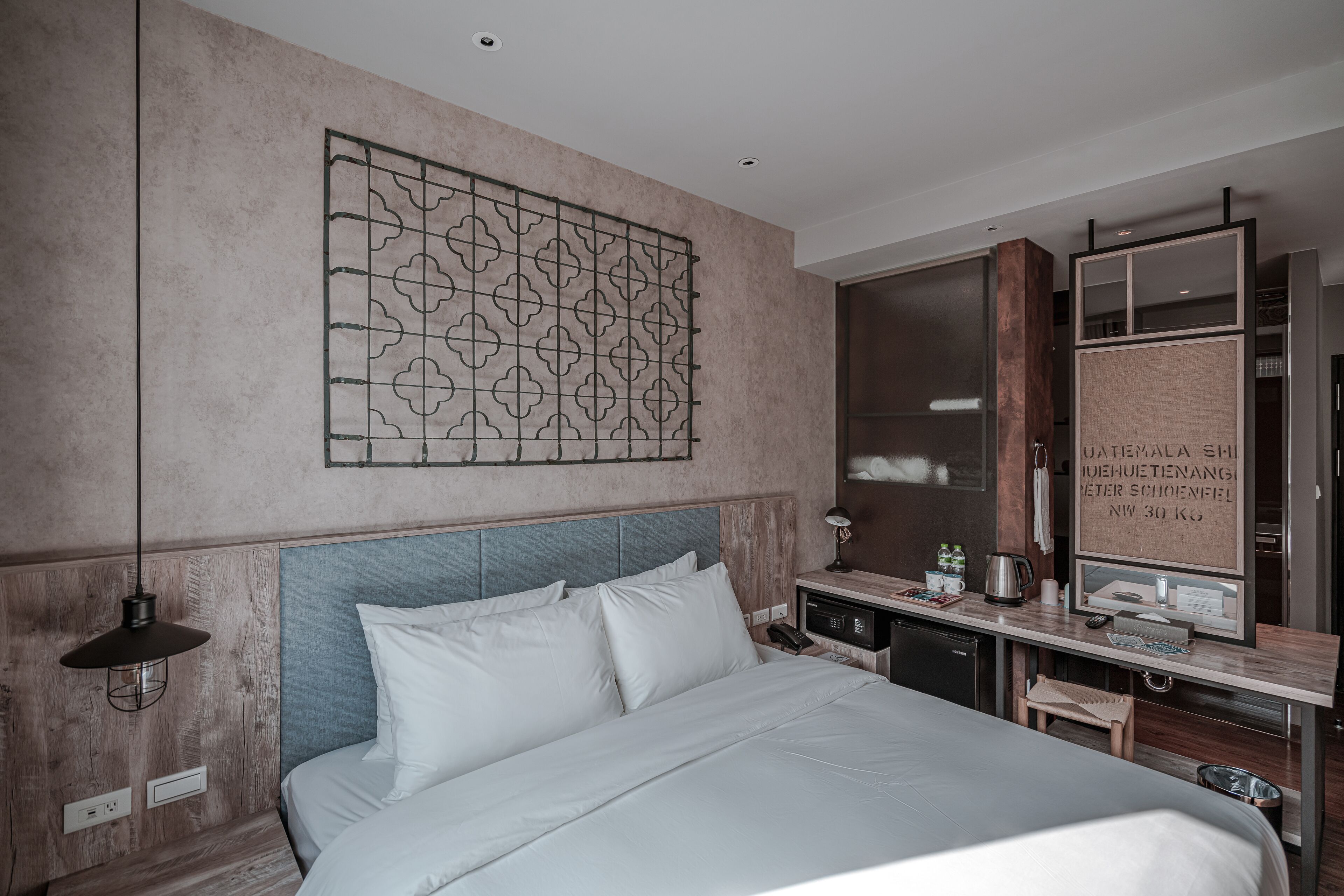 Een moderne hotelkamer met een groot bed, een bureau met een computer, een spiegel en een kledingkast.