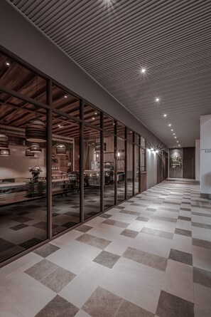 A modern hotel corridor with checkered flooring, glass walls, and wooden ceiling panels. - Somer Chew Hotel (Tainan)