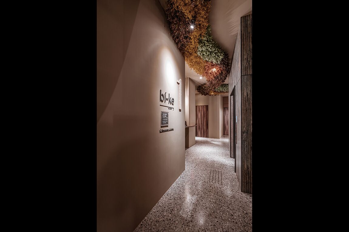 A hallway with a textured wall, a sign reading "b-f-k-e," and a decorative ceiling.