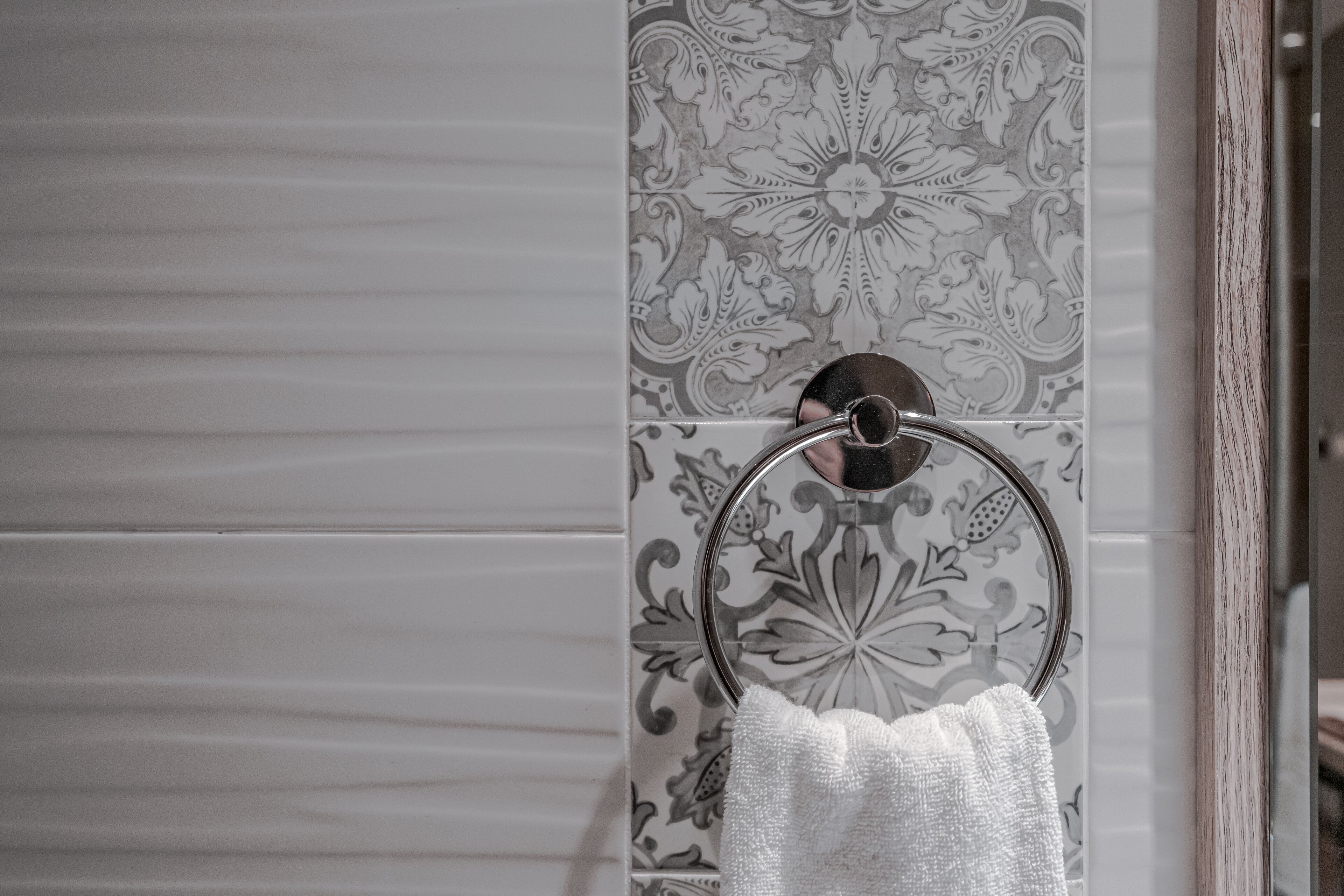 A bathroom with a towel ring and patterned tiles.