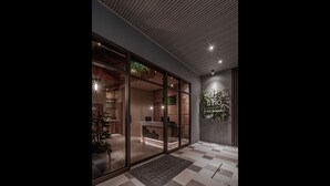 A hotel lobby with a checkered floor, a reception desk, and a large glass door leading to the interior. - Somer Chew Hotel (Tainan)