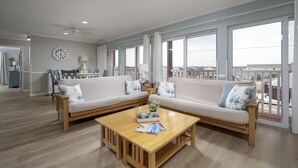 Ein geräumiges Wohnzimmer mit Couchtisch aus Holz, zwei Sofas und großen Fenstern mit Blick auf die Stadt.