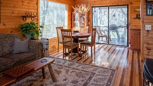 A cozy cabin interior with a wooden dining table, chairs, a sofa, and a fireplace. - Secluded Cabin Outside of Nashville - The Lodge at Oak Haven Farm (White Bluff)