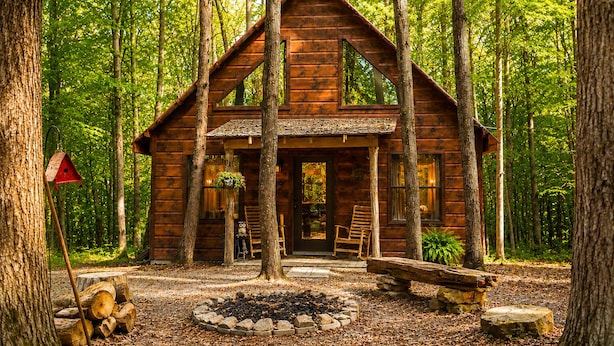 A wooden cabin with a porch, surrounded by trees. - Secluded Cabin Outside of Nashville - The Lodge at Oak Haven Farm (White Bluff)