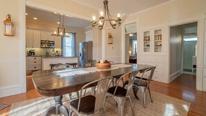 Un comedor amplio con mesa de madera y sillas metálicas, un candelabro y vistas a la cocina.