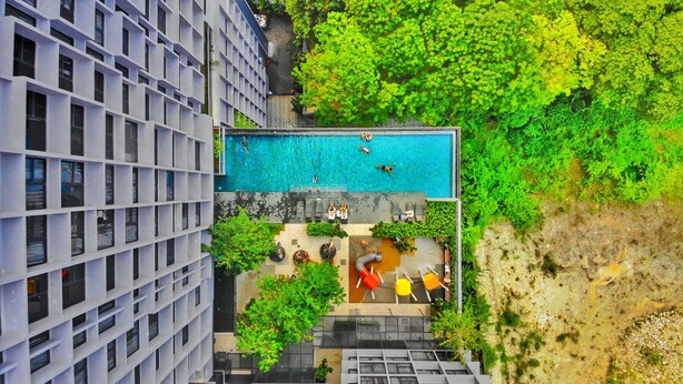 An aerial view of a modern building with a rooftop pool surrounded by greenery. - Expressionz Suites KLCC by Like Home (Kuala Lumpur)
