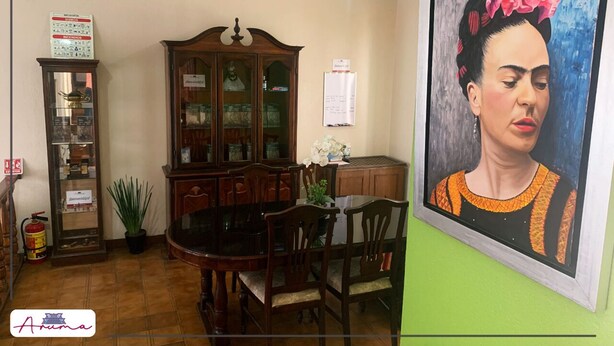 Zona pranzo con un mobile in legno, un tavolo, sedie e un quadro appeso al muro.