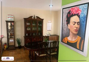 Un comedor con un armario de madera, una mesa, sillas y un cuadro en la pared.