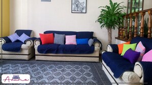 Un soggiorno con due divani, un tappeto decorato e una scala con ringhiera in legno.