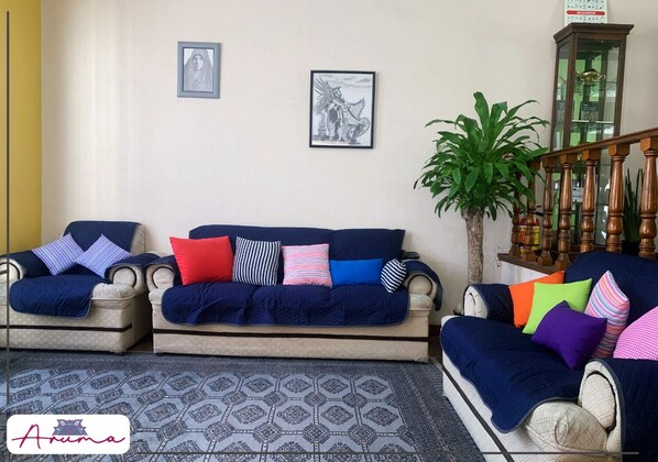 Una sala de estar con dos sofás, un tapete estampado y una escalera con barandilla de madera.