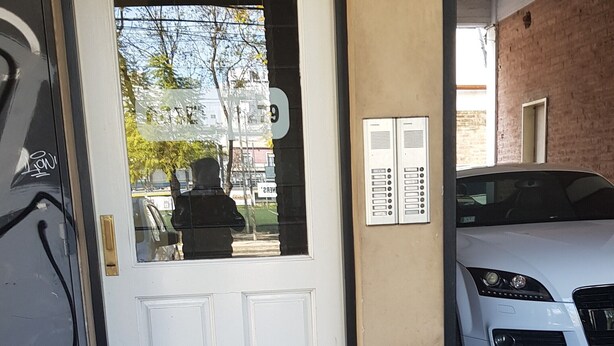 Una porta blanca amb un panell de vidre, un teclat numèric i una petita finestra.