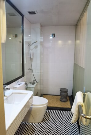 A bathroom with a white sink, a toilet, a shower, and a checkered floor.