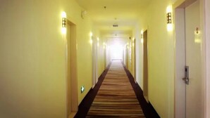 Een hotelhal met tapijttegels, deuren aan beide zijden en wandlampen.
