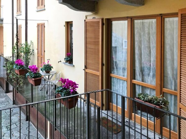 A balcony with potted plants, a table, and chairs.