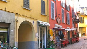 Uma rua de paralelepípedos com um terraço de restaurante, mesas ao ar livre e uma bicicleta estacionada na entrada.