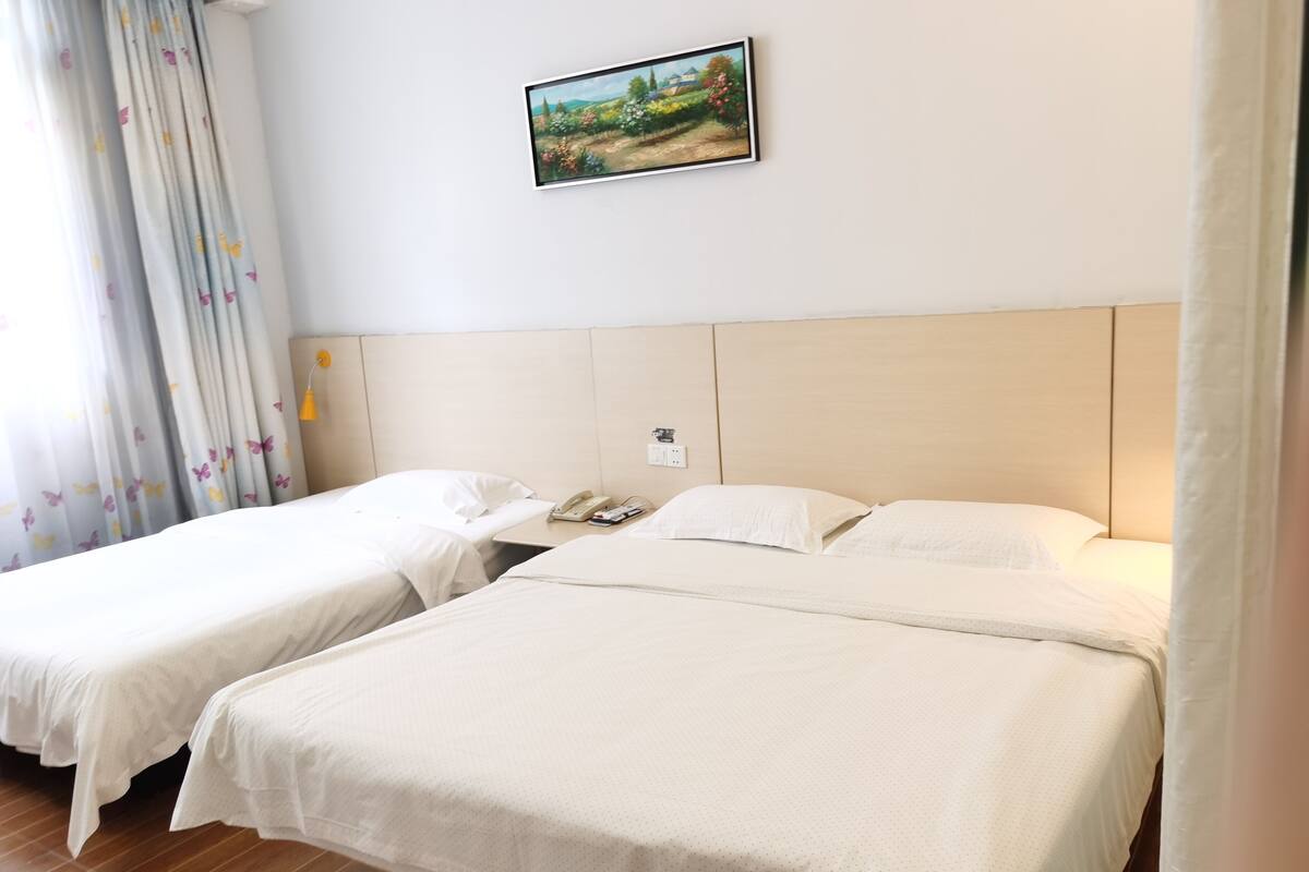 Habitación de hotel con dos camas individuales, un cuadro en la pared y un teléfono en la mesita de noche.