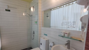 Un baño con ducha de vidrio, inodoro, lavamanos y un espejo con ventana superior.