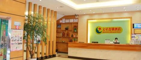 A reception area with a wooden reception desk, a large potted plant, and a wall with framed certificates.