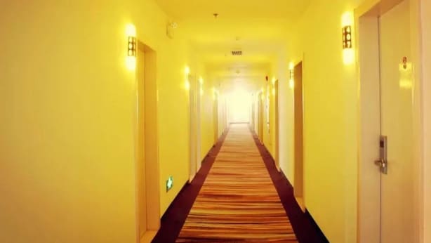 Un pasillo de hotel con suelo alfombrado y puertas a ambos lados.