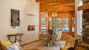 A cozy dining area with wooden chairs, a round table, and hanging light fixtures.