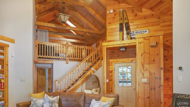 A wooden interior with a brown leather couch, a staircase, and a sign reading "AWK MOUNTAIN SANCTUARY".