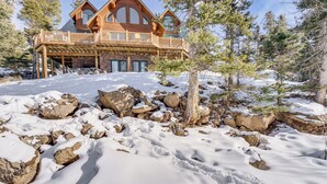 Une cabane en bois dotée d’un balcon, entourée de neige et de rochers.