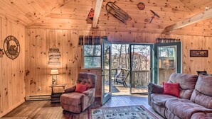 A cozy cabin interior with wooden walls, a plush sofa, a chair, and a rug. - 'Nature's Retreat' w/ Hot Tub: 7 Mi to Bryson City (Whittier)
